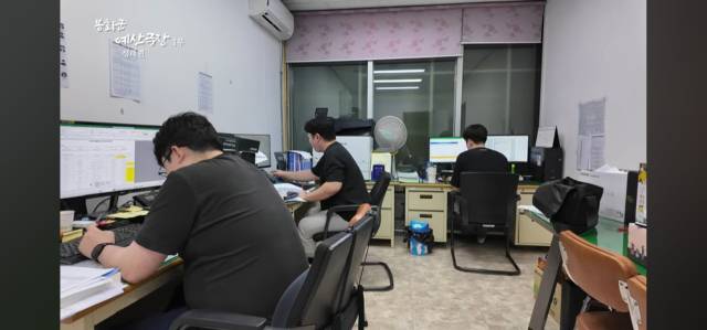봉화군청 예산팀 직원들이 좁은 사무실에서 빼곡한 책상과 모니터 사이로 예산 작업을 하는 모습이다. 자연광이 거의 없는 공간에서 여러 직원이 밀집해 근무하는 장면이다. 봉화군청 유튜브 캡처