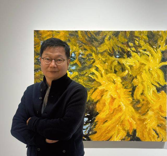 최선길 작가가 반계리 은행나무를 그린 자신의 그림 앞에서 카메라를 응시하고 있다. 최선길 제공