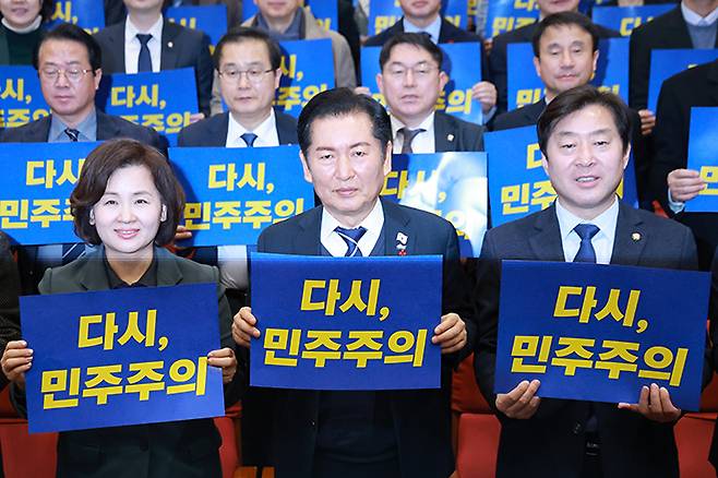 더불어민주당 정청래 대표가 3일 서울 여의도 국회의원회관에서 12·3 계엄 사태 1년을 맞아 열린 '행동하는 K-민주주의' 특별좌담회에 참석해 손팻말을 들고 구호를 외치고 있다. 연합뉴스