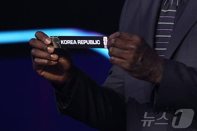 5일(현지시간) 미국 워싱턴DC 케네디센터에서 열린 2026 북중미 월드컵 조 추첨식에서 샤킬 오닐이 대한민국 카드를 뽑고 있다. 한국은 개최국 멕시코, 남아프리카공화국, 유럽 플레이오프 D조(덴마크, 북마케도니아, 체코, 아일랜드 승자)와 함께 A조에서 32강 진출을 두고 격돌한다. ⓒ AFP=뉴스1
