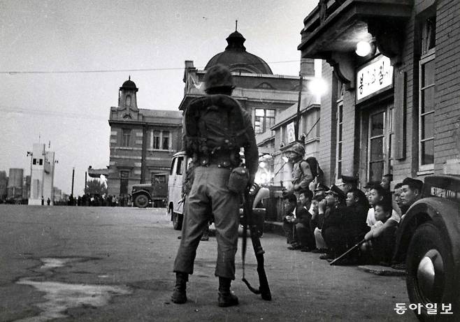 1961년5월16일 새벽 쿠데타를 일으킨 일단의 군인들이 서울역에서 행인들을 통제하고 있다. 시민들 사이에서 파출소 앞에 쪼그려앉은 경찰의 모습이 이채롭다. <이의택 촬영, 신동아 1984년 8월호>/ 동아일보 DB