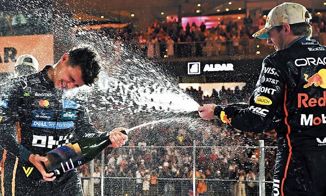 7일 UAE에서 열린 2025시즌 포뮬러원(F1) 최종전 아부다비 그랑프리에서 시즌 챔피언 등극을 확정한 맥라렌의 랜도 노리스(왼쪽)가 ‘절친’ 막스 페르스타펀(레드불)이 뿌리는 샴페인 세례를 받고 있다. 페르스타펀은 이날 레이스에서 1위를 했지만, 종합 점수에서 노리스에게 2점 뒤져 5시즌 연속 챔피언이 무산됐다./게티이미지코리아