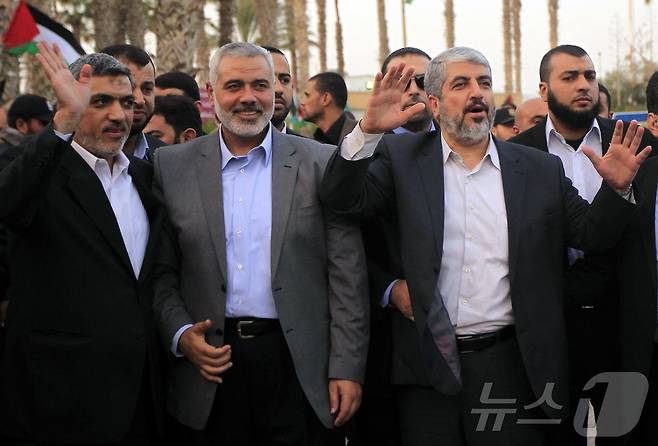 2012년 12월 가자지구를 떠나는 하마스 망명 지도자 칼레드 메샬(오른쪽)이 당시 하마스 총리 이스마일 하니야(가운데)와 하마스 지도자 이자트 알 리쉬크(왼쪽) 옆에서 작별 인사를 하고 있다. 2012.12.10. ⓒ AFP=뉴스1 ⓒ News1 이정환 기자