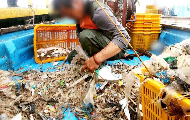 ▲ 2021년 한강하구 어민들이 새우잡이 조업을 하고 있다. 그물에 새우보다 쓰레기가 많이 걸려 있는 걸 확인한 어민이 허탈해하고 있다. /인천일보DB