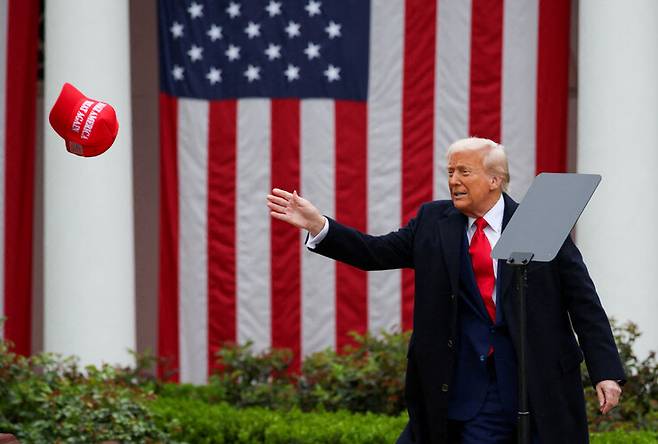 도널드 트럼프 대통령이 2025년 4월2일 백악관에서 관세 관련 발표를 한 뒤 ‘MAGA’ 모자를 받으려 하고 있다. REUTERS 연합뉴스