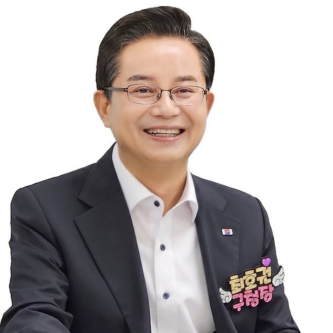 최호권 영등포구청장이 안경을 쓰고 미소를 지으며 정면을 응시하고 있는 사진이다. 검정색 양복 상의를 입고 있으며, 왼쪽 가슴에는 핀배지를 착용하고, 왼쪽 하단에는 ‘최호권 구청장’이라고 쓰여진 핑크색 배지가 부착되어 있다.