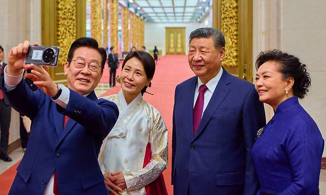 중국을 국빈 방문 중인 이재명 대통령과 김혜경 여사가 5일(현지 시간) 베이징 인민대회당에서 열린 공식만찬을 마친 뒤 시진핑 국가주석, 부인 펑리위안 여사와 경주 정상회담에서 시 주석에게 선물 받은 샤오미폰으로 셀카를 찍고 있다. 뉴시스