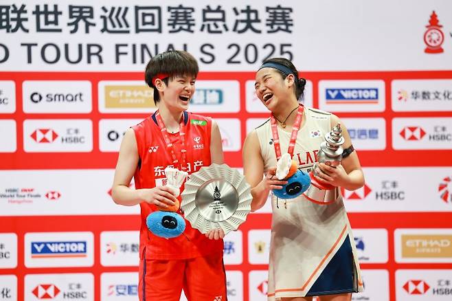 안세영(오른쪽)이 21일(현지 시간) 중국 저장성 항저우 올림픽스포츠센터에서 열린 2025 세계배드민턴연맹(BWF) 월드투어 파이널스 여자 단식 정상에 올라 시상대에서 왕즈이(중국)와 함께 웃으며 포즈를 취하고 있다. 안세영은 결승에서 왕즈이를 2-1(21-13 18-21 21-10)로 꺾고 우승하며 시즌 11승을 달성했다.뉴시스