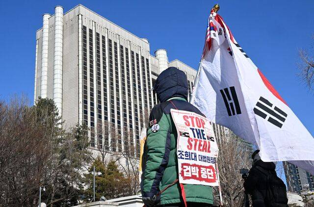 윤석열 전 대통령의 내란우두머리 혐의 결심공판이 열린 13일 서울중앙지법 앞에 윤 전 대통령 지지자가 태극기를 들고 서 있다. 권현구 기자