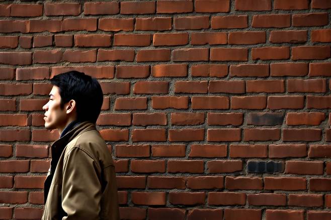 벽 앞에 서 있는 젊은 남성. 123rf