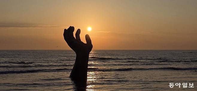 경북 포항시 남구 호미곶면의 대형 청동 조각상 ‘상생의 손’ 너머로 해가 떠오르고 있다. 포항=김선미 기자 kimsunmi@donga.com