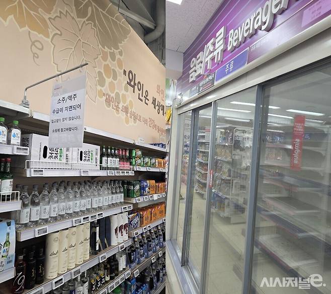 주류 판매대에 소주/맥주 수급이 지연돼 입고량이 많이 지연된다는 안내글이 적혀 있다(왼쪽). 오른쪽 사진은 텅 빈 냉장고 모습. / 사진=조건희 기자
