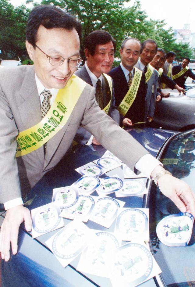 1998년 7월, 이해찬 당시 교육부 장관이 정부서울청사에서 주차된 차에 환경방학 캐릭터인 '베짱이' 스티커를 부착하고 있다. 한국일보 자료사진