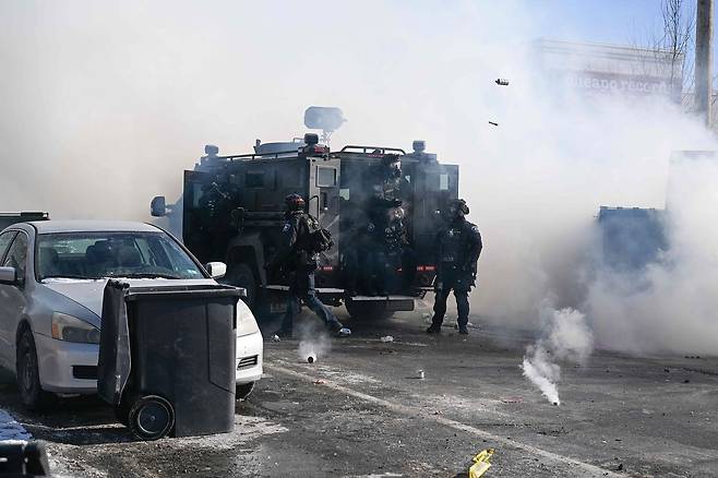 미네소타주 미니애폴리스에서 현지시간 24일, 연방 이민국 요원들이 한 남성을 사살한 현장 근처에서 경찰관들이 시위대를 향해 최루탄을 투척하고 있다.AFP=연합뉴스