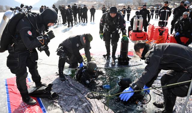 ▲ 27일 홍천 모곡유원지에서 동계 수난사고 대응 인명구조 훈련이 진행돼 소방관들이 얼음물 속으로 들어가고 있다. 방도겸 기자