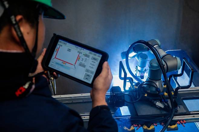 지난 7일 울산 남구 HD현대중공업 용연공장에서 작업자가 태블릿PC로 용접할 셀의 데이터를 불러온 뒤 로봇에 작업을 지시한 모습./HD현대중공업