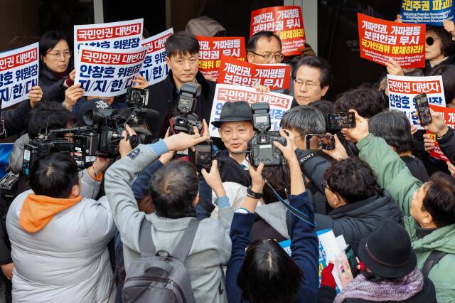 안창호 인권위원장이 지난해 12월10일 오전 서울 중구 안중근의사기념관에서 열리는 2025 인권의 날 기념식에 입장하려다 인권단체 활동가들에 의해 저지된 뒤 기자들의 질문을 받고 있다. 안 위원장(가운데) 오른쪽 뒤편으로 이날 “안창호를 지지한다”고 외치며 맞불시위를 벌인 주요셉 목사의 얼굴이 보인다. 공동취재사진