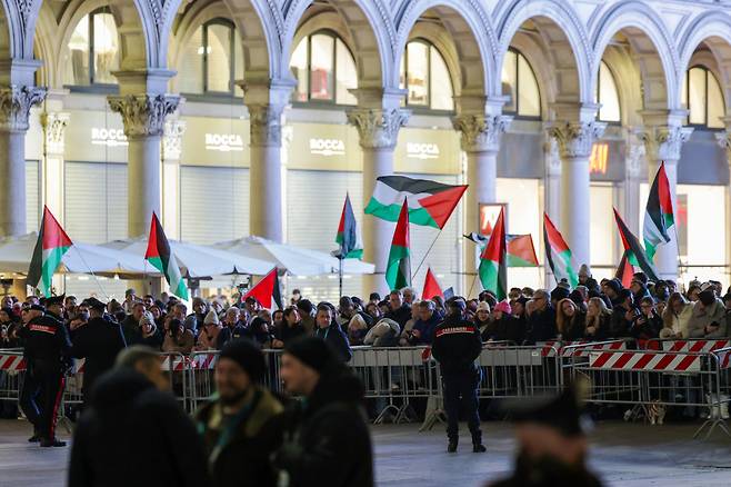2월 5일 저녁 이탈리아 밀라노 두오모 대성당 앞 광장에서 2026 밀라노 코르티나 동계 올림픽 성화봉송 행사가 열리고 있는 가운데 일부 사람들이 팔레스타인 국기를 내거는 시위를 하고 있다. 밀라노=장련성 기자