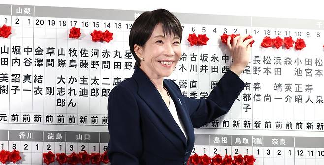 다카이치 사나에 일본 총리가 중의원(하원) 선거가 실시된 8일 도쿄의 자민당 당사에서 승리한 소속 후보들의 이름 위에 붉은 꽃 장식을 달아주며 활짝 웃고 있다. NHK방송에 따르면 자민당은 이날 오후 10시 40분 기준 전체 465석 중 과반(233석) 이상인 256석을 확보했다. 아사히신문 제공