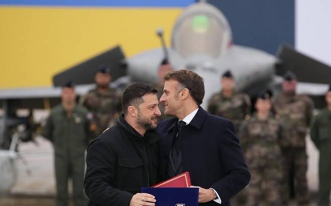 지난해 11월 17일 에마뉘엘 마크롱 프랑스 대통령(오른쪽)과 볼로디미르 젤렌스키 우크라이나 대통령이 파리 근교 빌라쿠블레 공군기지에서 열린 서명식 후 포옹하고 있다. EPA 연합뉴스