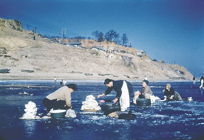 1948년 겨울 꽁꽁 언 한강 위에서 어머니들이 빨래를 하고 있다. 황량한 언덕 위에 집들이 눈에 들어온다. / 눈빛 아카이브