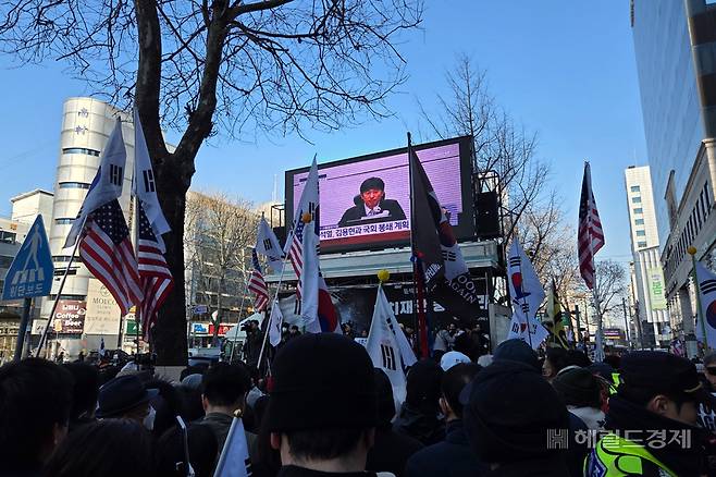 19일 오후 3시께 서울 서초구 서울중앙지방법원 앞 도로에서 열린 윤석열 전 대통령 지지 집회. 집회 참가자들이 대형 전광판을 통해 내란 우두머리 혐의 선고 공판을 지켜보고 있다. 이영기 기자.