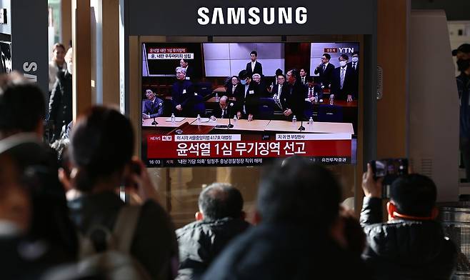 19일 오후 서울역 대합실에 설치된 TV를 통해 윤석열 전 대통령의 내란 우두머리 혐의 1심 선고가 생중계 되고 있다. 뉴스1