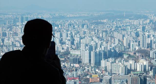 지난 19일 서울 남산 N서울타워에서 시민이 집합건물(아파트·연립·오피스텔 등) 중심 지역을 바라보고 있다. 연합뉴스