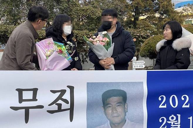 지난 11일 오후 전남 해남군 해남읍 광주지법 해남지원 법정 앞에서 보험금을 노려 아내를 살해한 혐의로 무기징역을 받았던 고(故) 장동오씨의 유족이 재심 무죄 선고에 따른 축하 꽃다발을 받고 있다. 연합뉴스