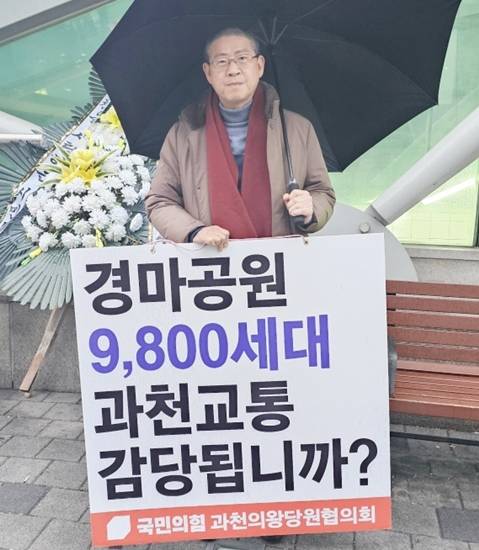 최기식 국민의힘 과천·의왕 당원협의회 위원장이 과천시에서 ‘경마공원 9천800세대 과천교통 감당됩니까?’라는 문구가 적힌 팻말을 들고 1인시위를 벌이고 있다. 최기식 국민의힘 과천·의왕 당원협의회 위원장 제공
