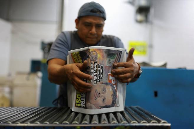 22일(현지 시각) 멕시코 시우다드 후아레스에서 한 신문사 직원이 마약왕 네메시오 오세게라(일명 '엘 멘초')가 사살된 기사가 실린 신문을 분류하고 있다./로이터 연합뉴스