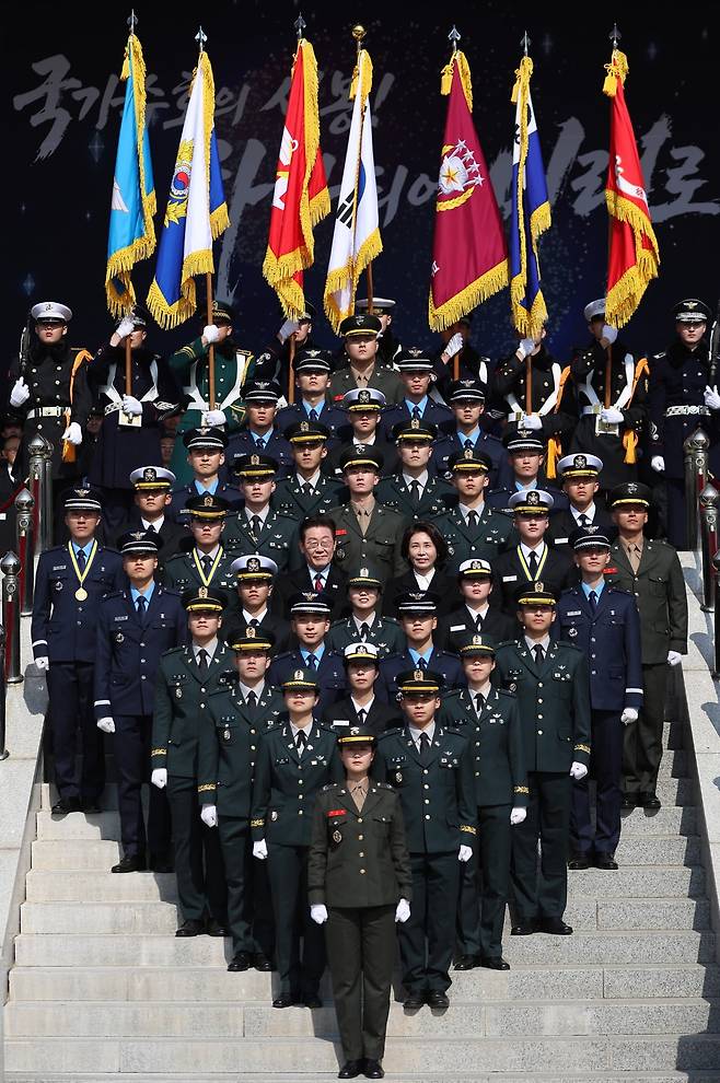 이재명 대통령과 김혜경 여사가 지난 20일 충남 계룡대 대연병장에서 열린 육·해·공군 사관학교 통합임관식에서 신임 장교들과 기념촬영을 하고 있다. 뉴스1