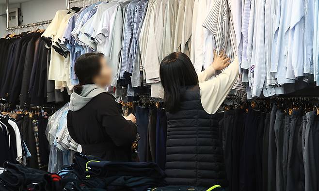 교복값 잡힐까 교육부가 전국 중?고등학교 약 5700곳을 상대로 교복비 관련 전수조사에 나서는 등 ‘교복 가격 개선방안’을 발표한 26일 서울 송파구의 한 나눔교복매장에서 학부모가 교복을 고르고 있다. 연합뉴스