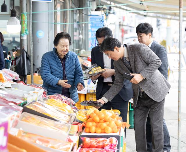 김돈곤 청양군수가 청양전통시장에서 과일을 고르며 농어촌 기본소득을 사용하는 모습