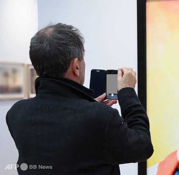 사진은 칼럼 내용과 관련 없습니다. 한 갤러리가 전시장에서 휴대폰으로 작품을 촬여하는 모습입니다. 사진제공=ⓒAFPBBNews = News1 (사진을 무단으로 사용하지 마십시오)