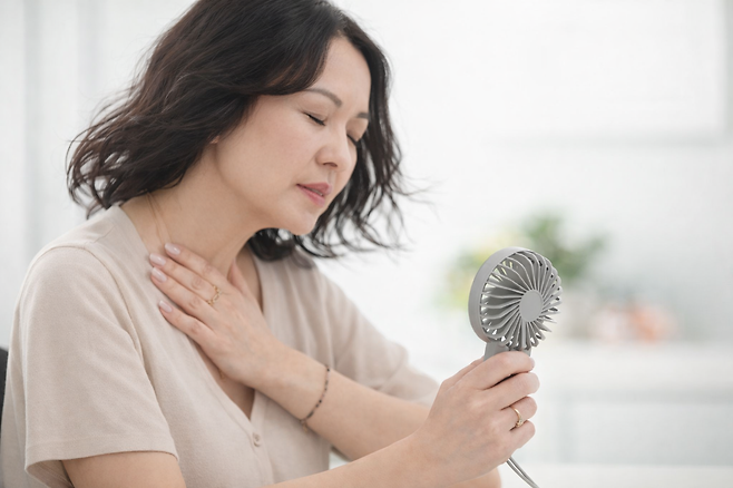 손풍기로 열을 식히는 여성