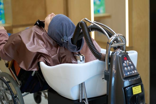 '헤어카페 더 휴 상계점'을 방문한 한 손님이 맞춤형 샤워도기에 누워 헤어클리닉을 받고 있다. /노원구