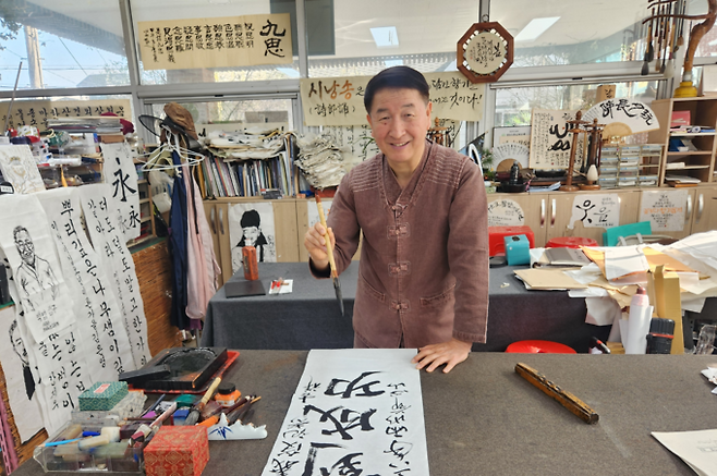 ▲ 강성태 서예가가 작업실에서 작품을 완성하며 환하게 웃는 모습. 서의수 기자
