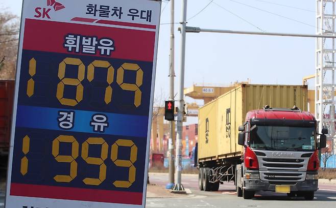 중동 사태로 국제 유가가 급등하면서 유류비 부담이 커진 화물차 기사들이 어려움을 호소하고 있는 가운데 10일 경유 가격이 1999원으로 적혀 있는 부산 강서구 부산신항 인근 한 주유소 유가 안내판 뒤로 화물차들이 지나가고 있다. 2026.3.10 뉴스1