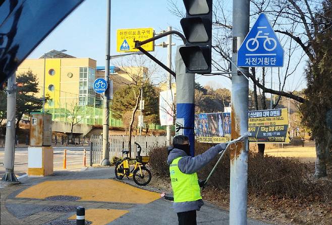 유성구청 직원이 어린이 보호구역 내의 불법광고물을 정비하고 있다. (사진= 대전 유성구)
