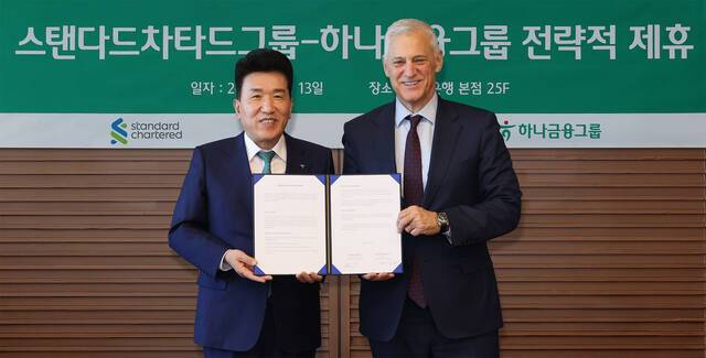 하나금융그룹은 지난 13일 서울 중구 하나은행 본점에서 영국의 글로벌 금융그룹 스탠다드차타드와 글로벌 비즈니스 및 디지털 자산 협력을 위한 업무협약을 체결했다. 이날 협약식에 참석한 함영주 하나금융그룹 회장(왼쪽)이 빌 윈터스 스탠다드차타드그룹 회장(오른쪽)과 협약서를 들고 기념촬영을 하고 있다. /하나금융그룹