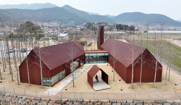 고성군 대가면 대가연꽃테마공원에 위치한 제정구 커뮤니티센터는 단순한 집 형태의 박공지붕 건물 두 채를 병렬로 배치해 거대한 공공건축 대신 마을 규모에 맞는 친근한 공간 구조를 구현했다.