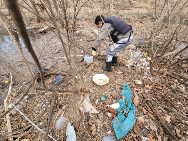 ▲카누를 타고 도착한 춘천 상중도 부근 강변에서 이원도 씨가 나무를 정리하고 있다. 육지가 아니었지만 키가 작은 나무 사이로 쓰레기가 모이고, 나뭇가지와 쓰레기가 잘게 잘려 쌓이면서 ‘쓰레기섬’이 됐다.