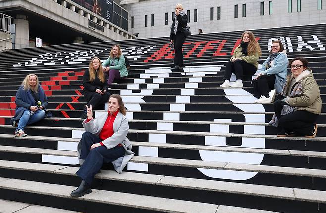 2026년 3월 18일 서울 종로구 세종문화회관 계단에서 폴란드에서 온 관광객들이 방탄소년단 컴백 공연 광고 문구와 기념촬영을 하고 있다. /장경식 기자