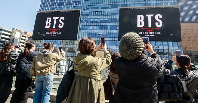 방탄소년단(BTS) 컴백 공연을 앞둔 19일 서울 종로구 광화문광장 인근에서 시민과 외국인관광객들이 건물 옆에서 송출되는 공연 광고를 촬영하고 있다. 이들은 광고가 나오는 순간을 찍기 위해 평균 15분 정도를 기다렸다. 유희태 기자