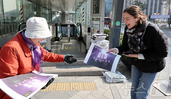 방탄소년단(BTS) 완전체 컴백 공연을 앞둔 21일 오전 서울 을지로입구역에서 독일인 관광객이 한국경제신문의 BTS 특별판 호외를 받고 있다. 2026.3.21 ⓒ 뉴스1 김진환 기자