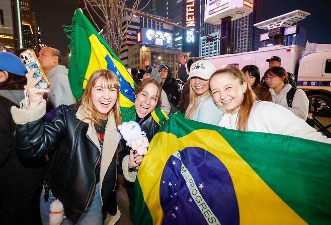 방탄소년단(BTS) 광화문 컴백 공연이 열린 21일 서울 종로구 광화문 광장에서 브라질인 아미(BTS 팬덤 명칭)가 국기를 들고 공연을 지켜보고 있다.