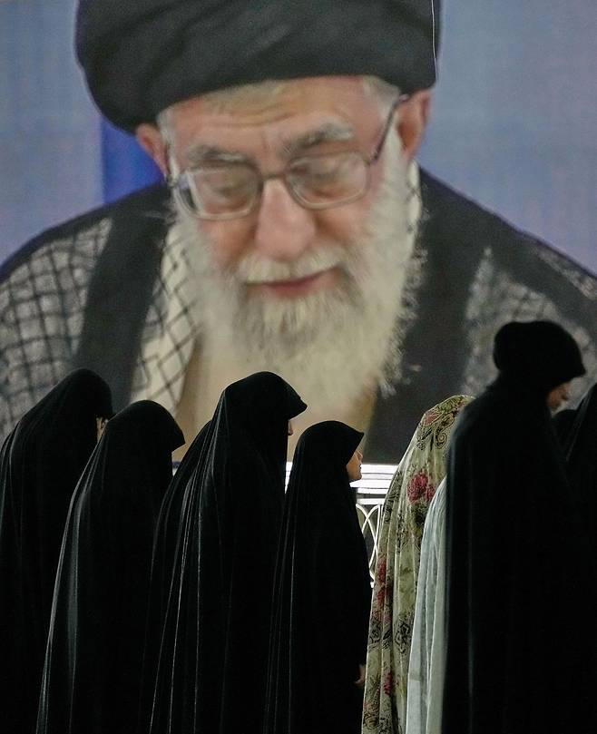 21일(현지시간) 이란 테헤란 이맘 호메이니 모스크에서 아야톨라 알리 하메네이 최고 지도자의 사진을 배경으로 이란인들이 기도를 하고 있다. AP=연합뉴스