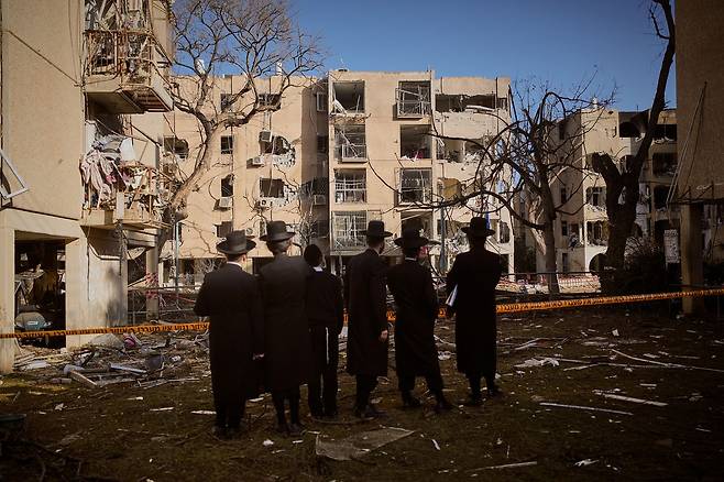 22일(현지시간) 이스라엘 아라드에서 시민들이 이란의 미사일 공격으로 피해를 입은 주택들을 바라보고 있다. AP=연합뉴스