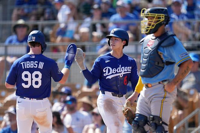 Los Angeles Dodgers' Hyeseong Kim (6), of South Korea, and James Tibbs III (98) celebrate their runs scored as Milwaukee Brewers catcher Gary Sanchez pauses near home plate during the third inning of a spring training baseball game, Monday, March 16, 2026, in Phoenix. AP연합뉴스